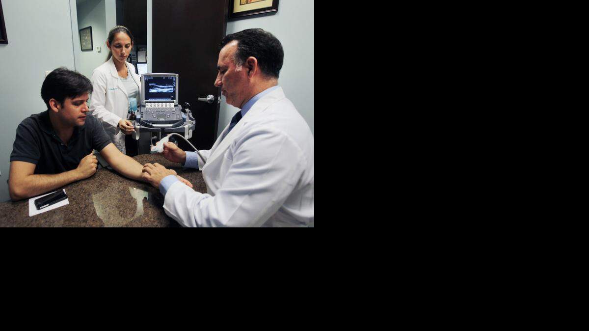 
El Dr. Alejandro Badia (der.) con el paciente Jorge A. Sánchez. Al fondo, Dr. Kale Samuels, en el Badia Hand to Shoulder Center en Doral.
