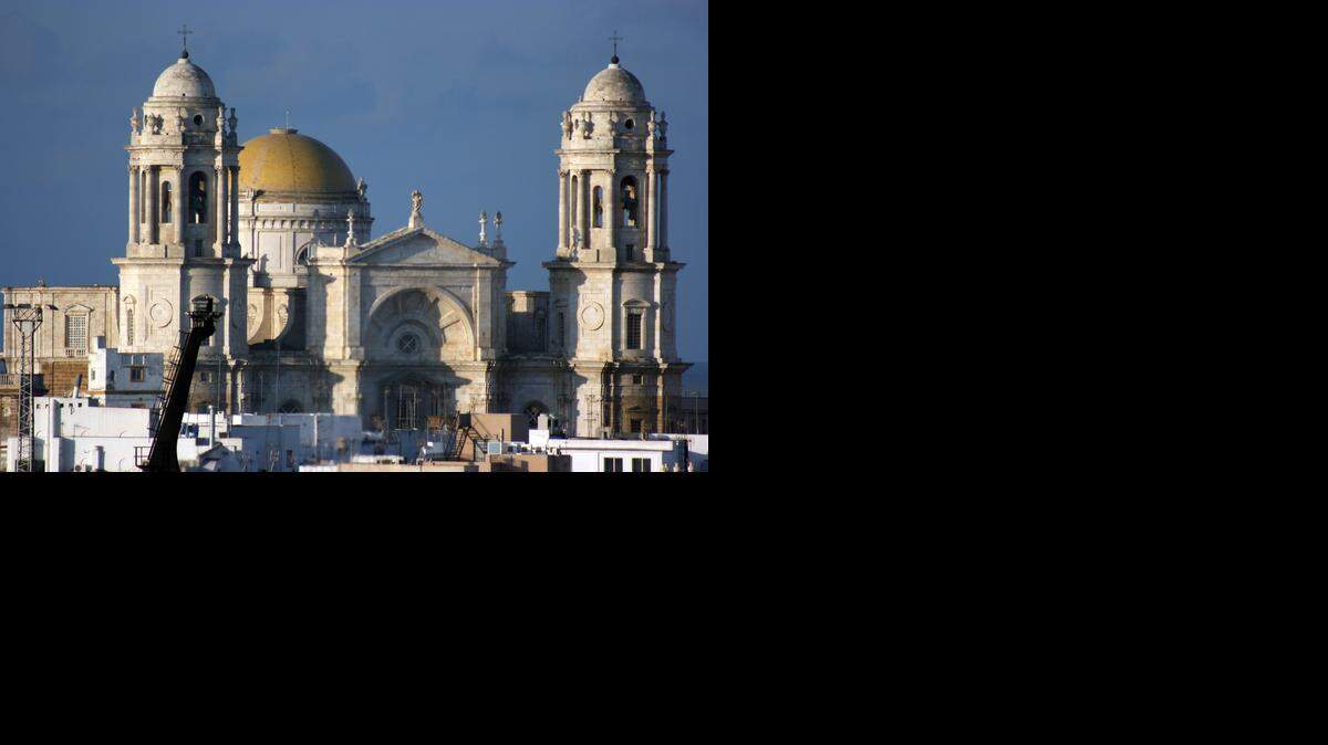 
Fachada de la Catedral de Cádiz vista desde el puerto. En el centro resplandece su cupula dorada. A la derecha de la entrada principal está la llamada Torre del Poniente desde cuyo mirador es posible ver toda la ciudad.

