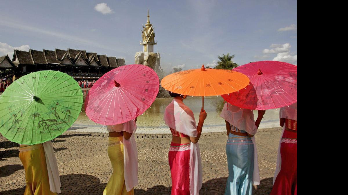 
Jóvenes de la minoría étnica Dai llevan paraguas de colores vistosos durante una función del Festival de salpicar con agua en un pueblo turístico al lado del río Mekong en la prefectura autónoma de Xishuangbanna Dai en la provincia de Yunnan al sudoeste de China. 

