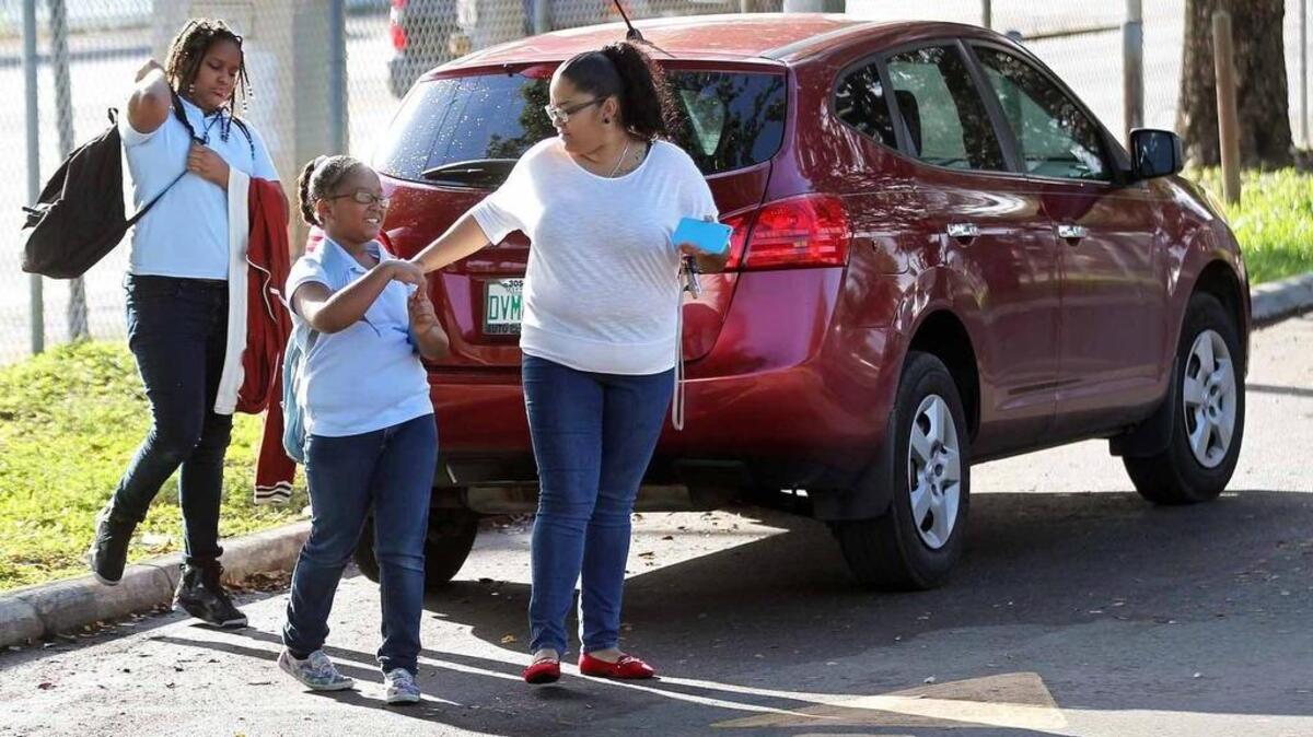 La mamá, Angie Morales (der.), deja a sus hijas Luizanyi y Tanyi en la escuela primaria de Hialeah.